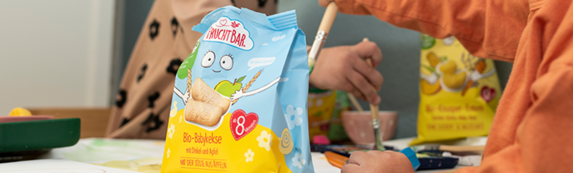 Bio Kekse für Babys - Foto von zwei Kleinkindern am Maltisch mit Snack-Teller